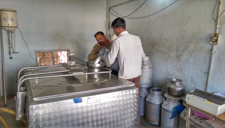 Two men pouring milk into machine