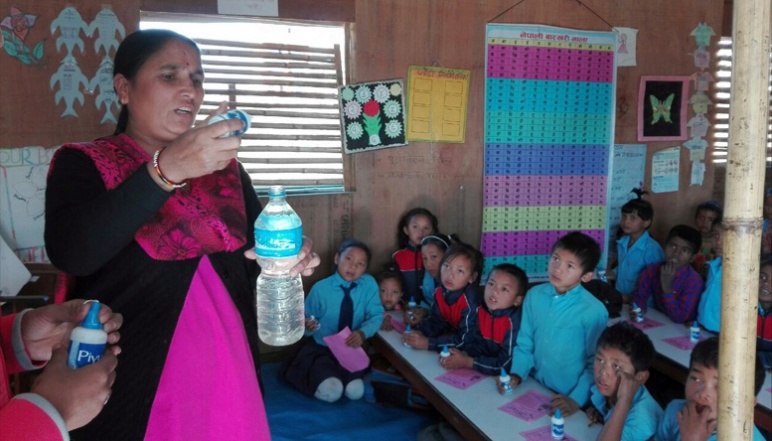 Woman holding water bottle teaching school children how to santize water