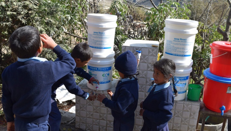 Children getting water from filtered white buckets