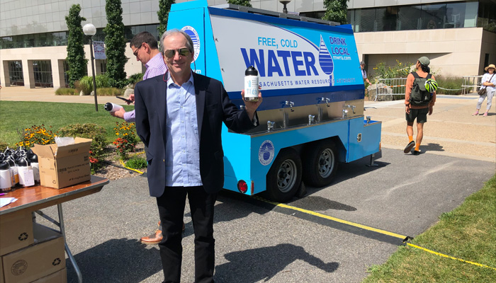 John Lienhard holds water bottle in front of water filling station