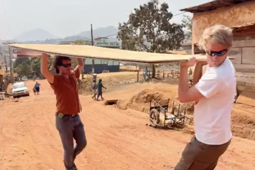 D-Lab researcher Daniel Sweeney and MIT student Will Reinkensmeyer moving a piece of wood to make the brooder