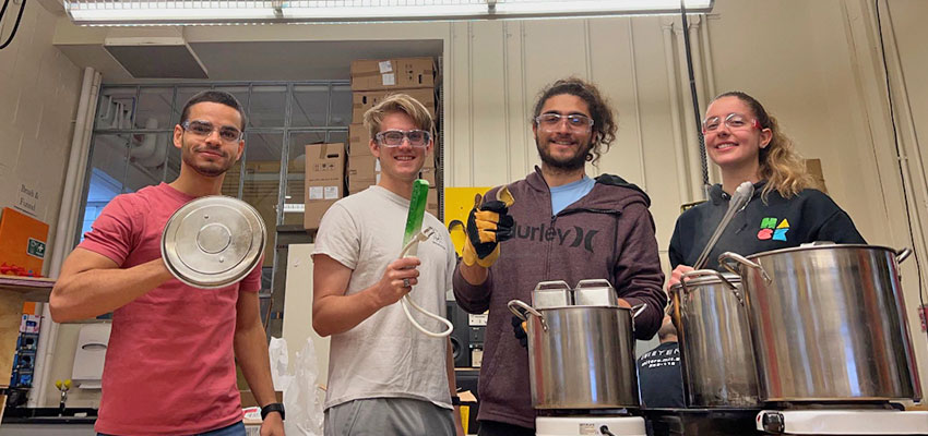 Department of Mechanical Engineering: Katana Finlason, Aly Kombargi, Will Reinkensmeyer, and Ahmad Zakka, in the lab with large metal pots and devices used to make their thermal batteries