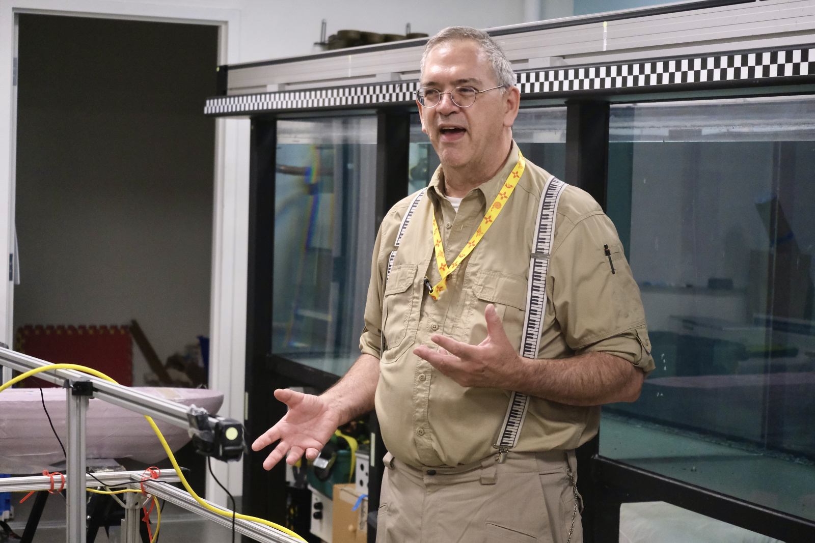 Andrew Bennett addresses an audience in front of a large water tank in the MIT Sea Grant lab facilities