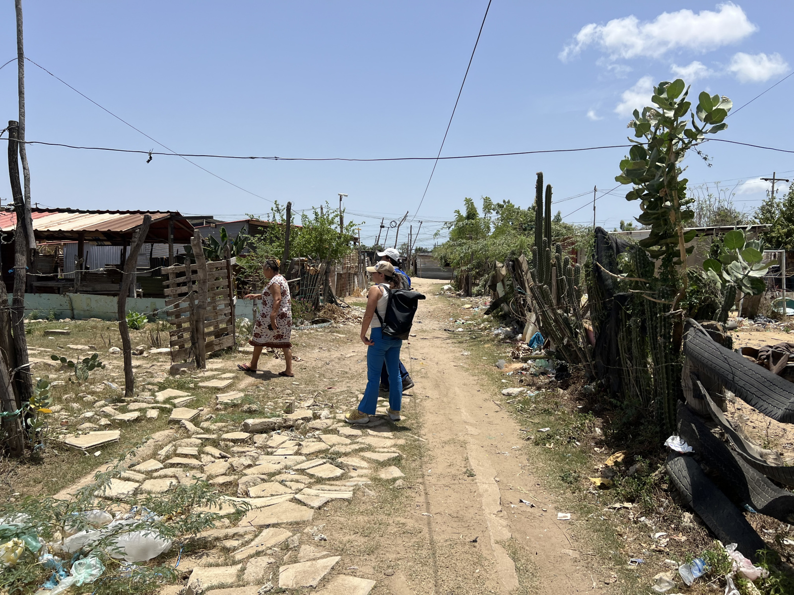 Three people standing on a rocky pathway. two are stopped in the middle looking at their surroundings while the other continues moving