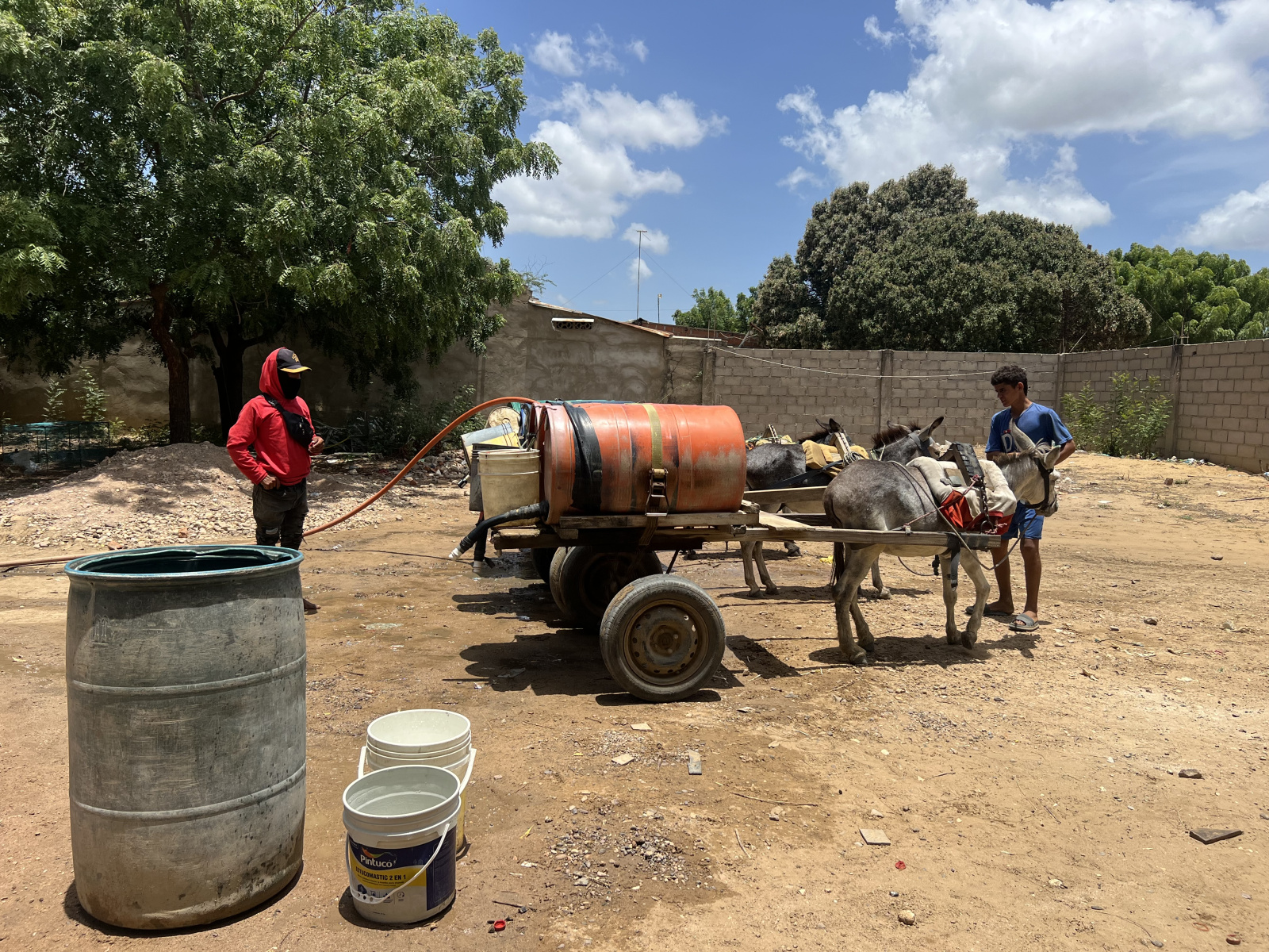 Two men using a donkey-drawn carriage to transport barrels of water