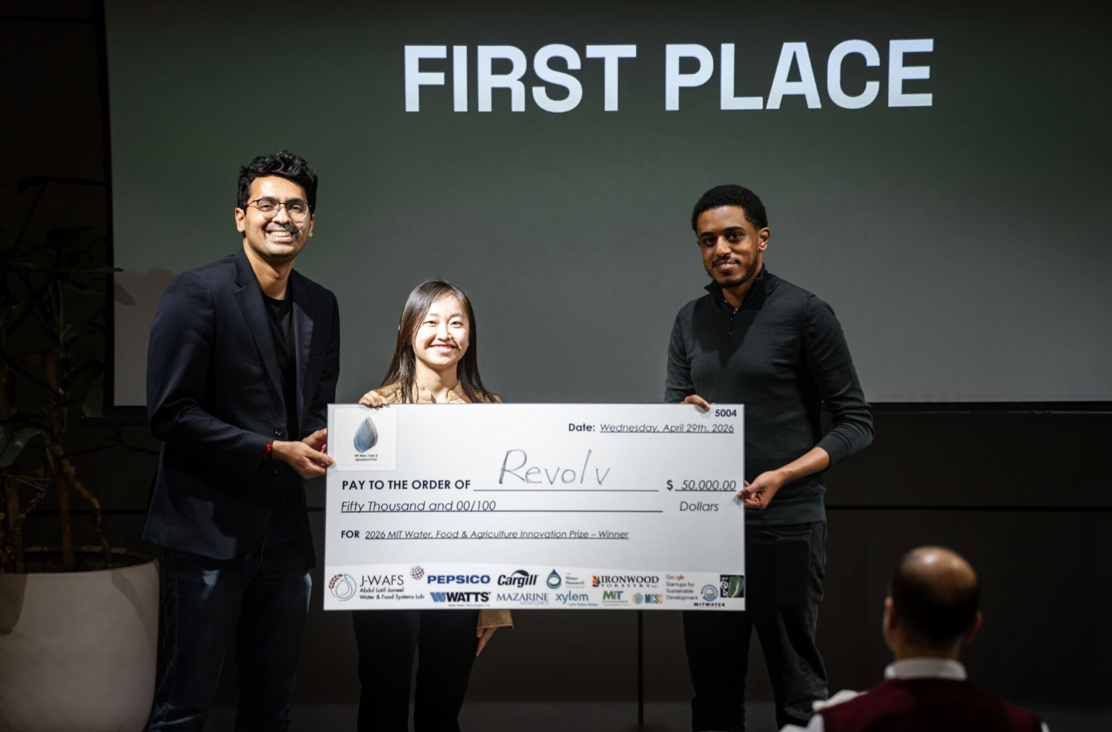 3 people hold novelty check for $50,000 in front of First Place sign