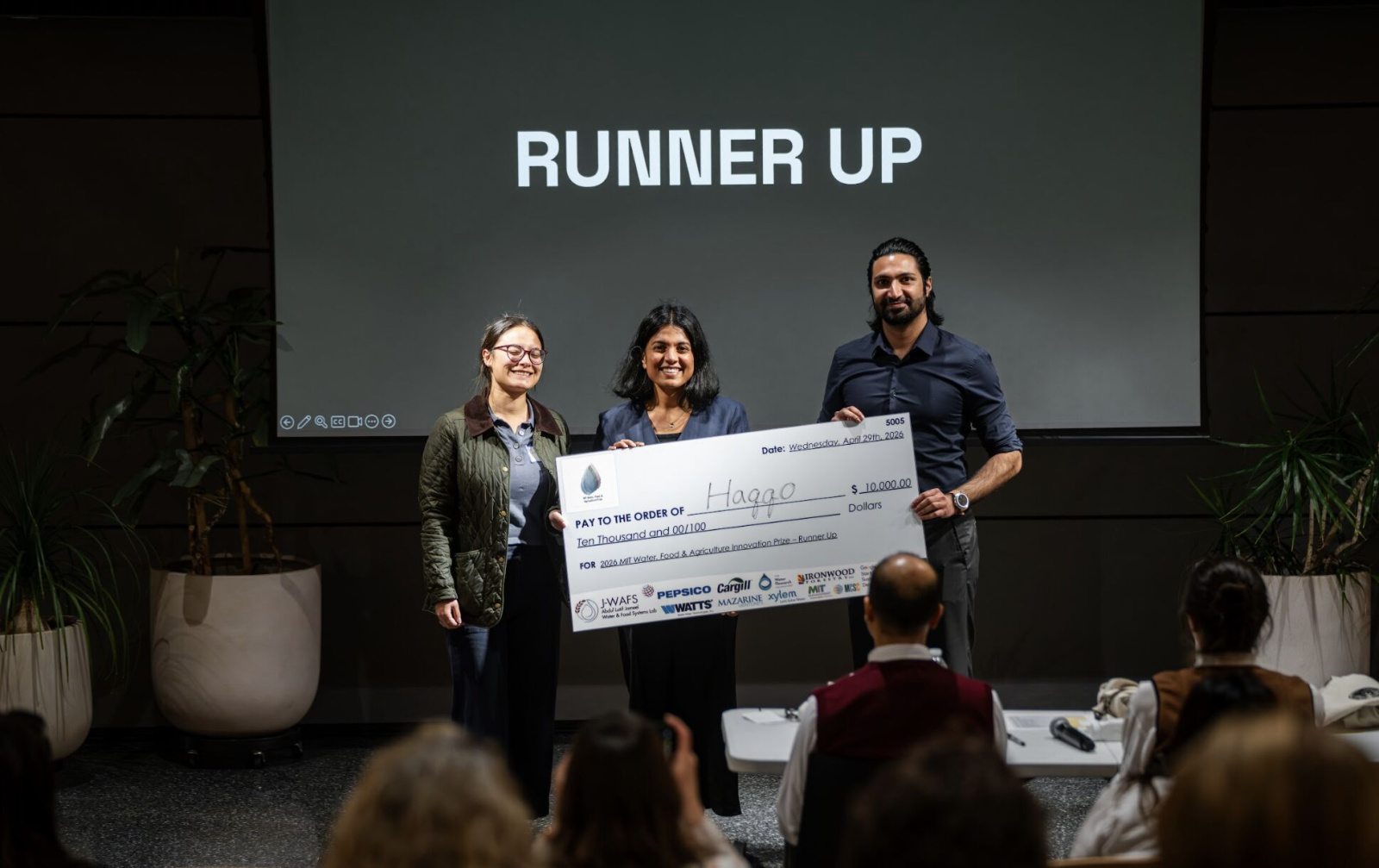 3 people hold novelty check for $10,000 in front of runner up sign