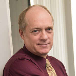 Professor Tim Swager in a red shirt and tan tie