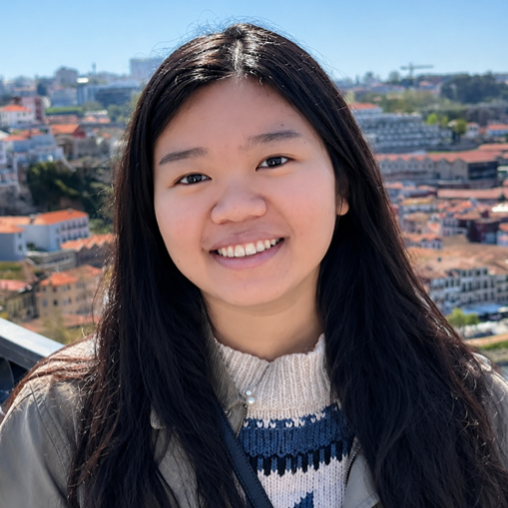 Hao Nghi Luu stands outside above what looks like a European city along a river 
