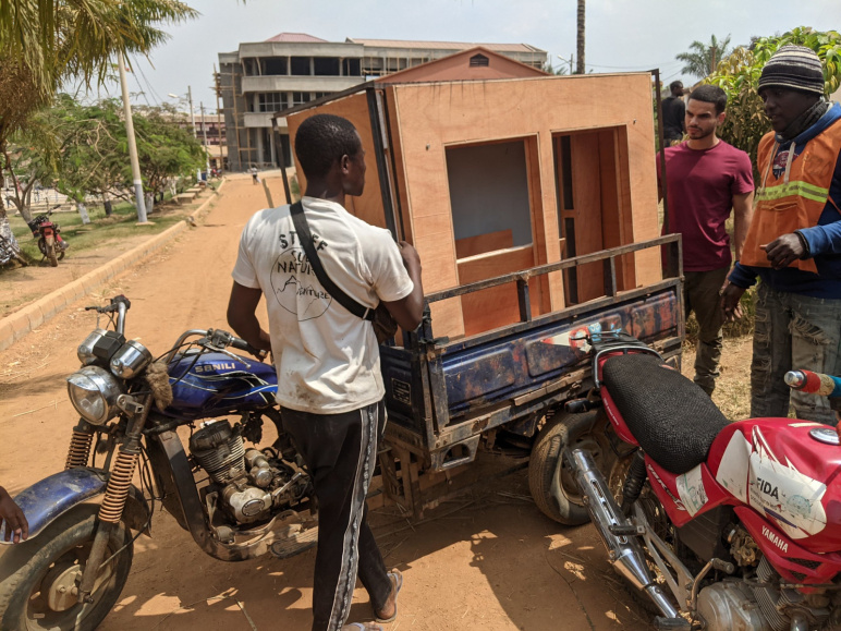 Three people transporting the Off-Grid Brooder v2 prototype