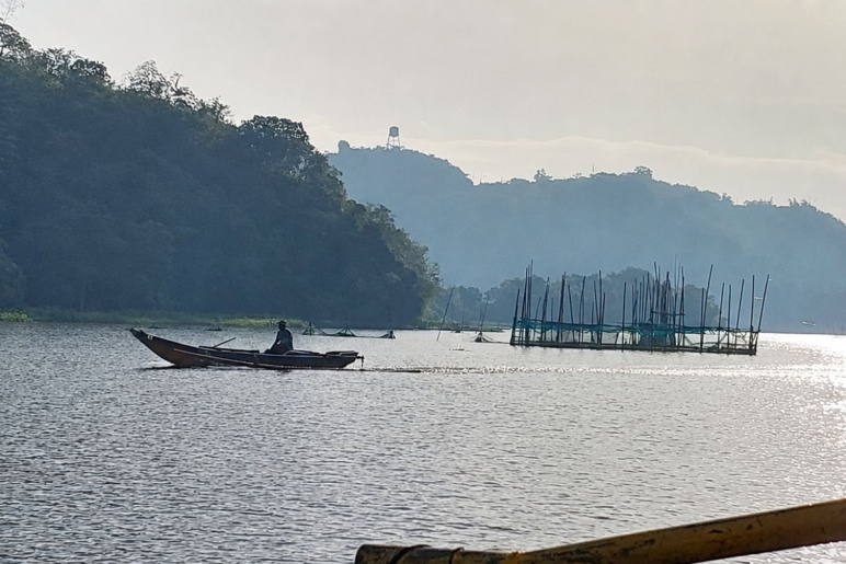 Laguna Lake in the Philippines with small mountains in the background and a person on a canoe-like boat