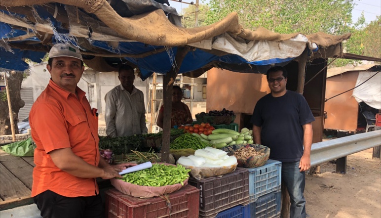 Men standing around crates of vegetables