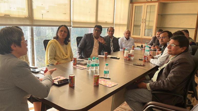 A group of people sit around a conference room table talking 