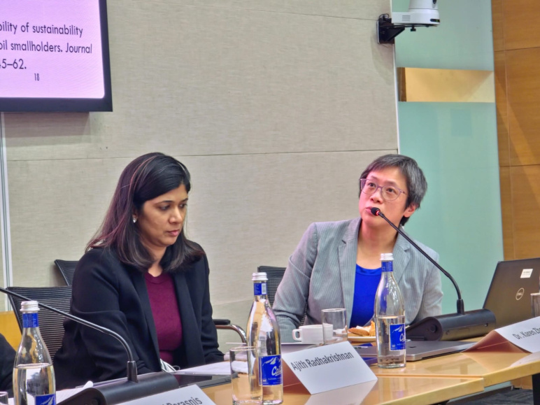Prof. Zheng sits in front of a microphone next to another woman at a workshop