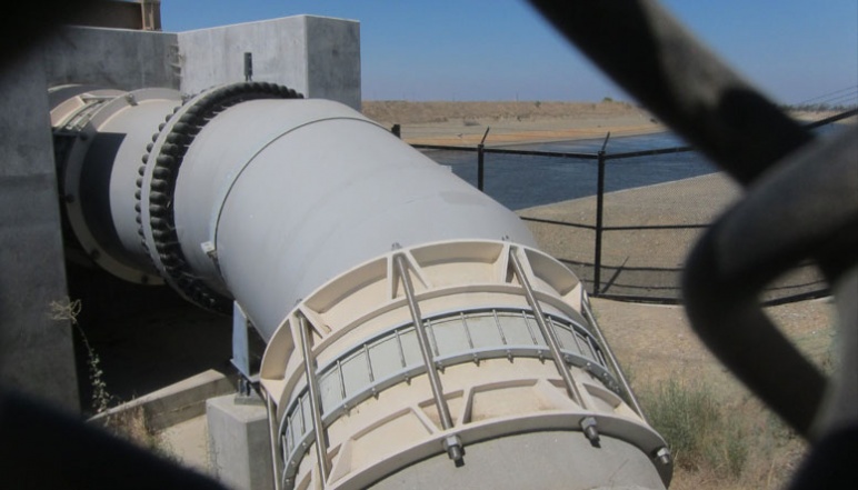 Picture of large pipe by side of river taken through fence