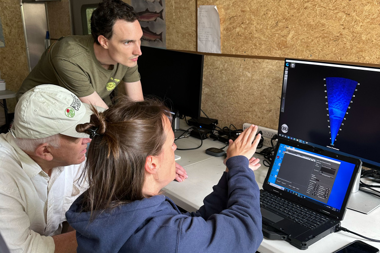 Three researchers look at sonar on a laptop and monitro