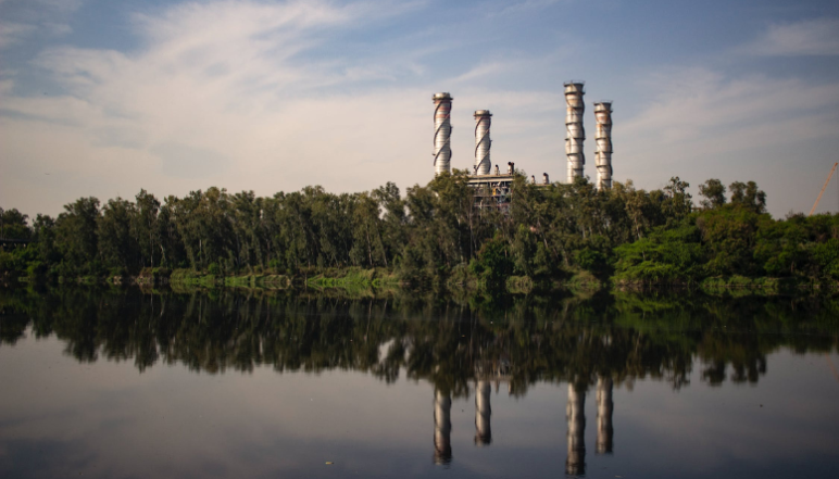 A factory surrounded by tree and next to a river 