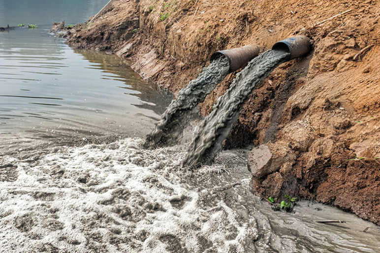 Dirty water rushing out of two big pipes into a river