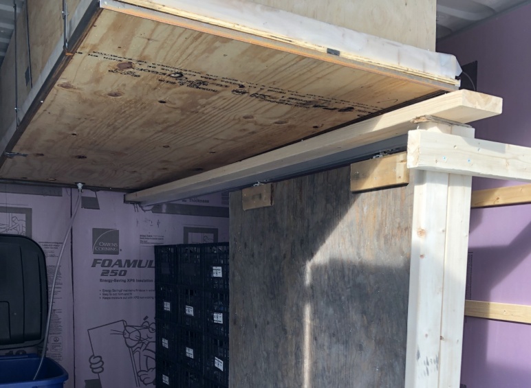 Image of experimental storage area inside the shipping container with the door slid open to allow the removal and placement of crates (black)