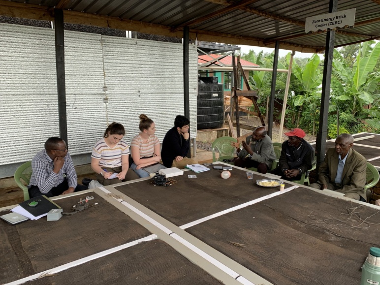 Image of MIT and University of Nairobi students sitting at table with members of a farming cooperative in Karurumo, Kenya