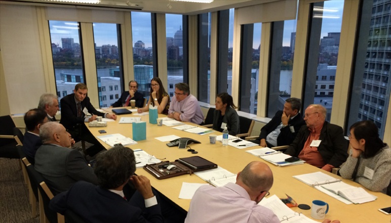 People sitting around table with Boston skyline in background