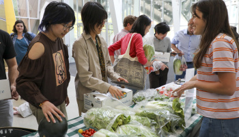 Two people buying various produce items from a seller