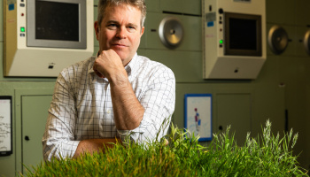 Headshot of J-WAFS PI David in front of bio technology and green plant grass at bottom forefront