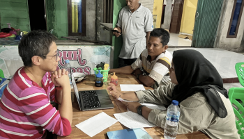 Four individuals sitting at a table discussing a project on a computer