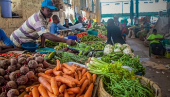 A man displaying harvested crops at an indoor market. 