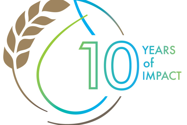 The icon from the J-WAFS anniversary logo featuring our signature swirl of wheat intertwined with a water drop and the number 10 with the words years of impact