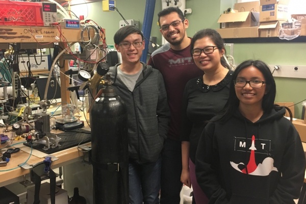 Four student researchers smile in front of a lab bench