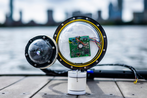 A prototype camera sitting on a dock with the Charles River and Boston in the background
