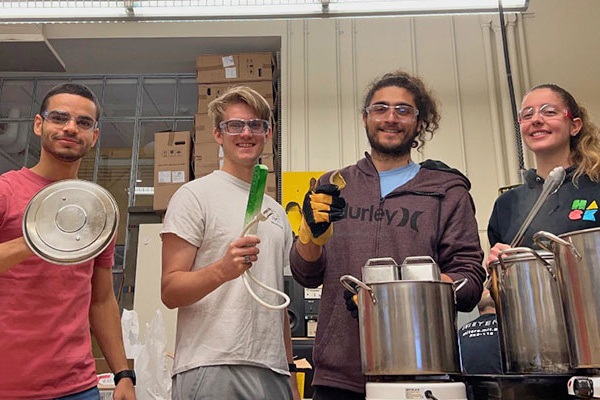 Department of Mechanical Engineering: Katana Finlason, Aly Kombargi, Will Reinkensmeyer, and Ahmad Zakka, in the lab with large metal pots and devices used to make their thermal batteries