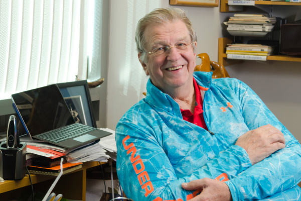 Anthony Sinskey sitting at a desk wearing a light blue shirt crossing his arms and smiling. 