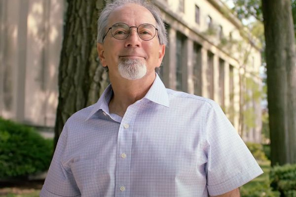 John Lienhard in a white button down shirt standing outside an MIT building