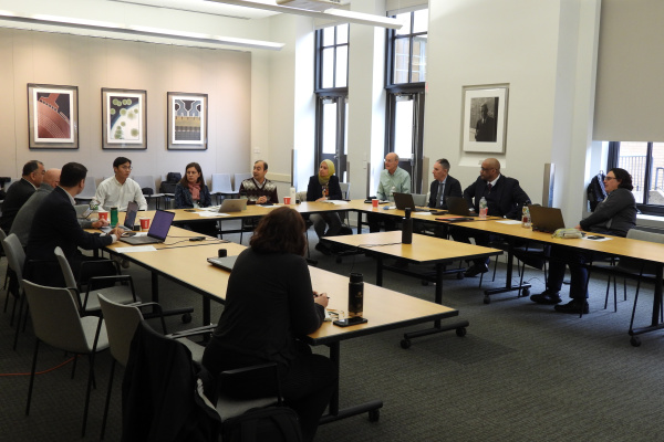 A large group of people sitting around tables put together in the shape of a "U" at a workshop