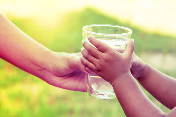 Adult hands child a cup of water