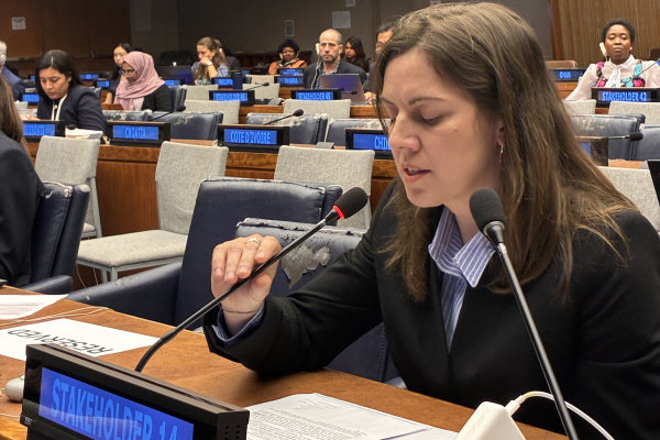 Daniela Giardina sits in front of two microphones speaking at the United Nations
