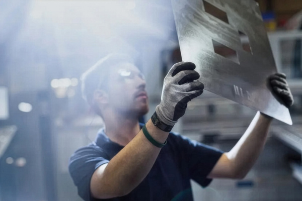 Peter Godart looks at a large sheet of metal he is holding up to the light