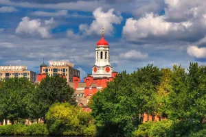 A scenic view of Harvard University buildings, highlighting a red-and-white clock tower.