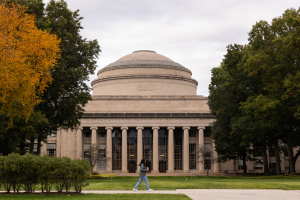 a person walking in front of a MIT building