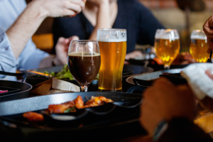 A group of people sitting at a table with beer and food