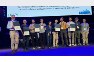 J-WAFS PI Sara and team standing on stage, holding PAMI prize certificates, blue floor