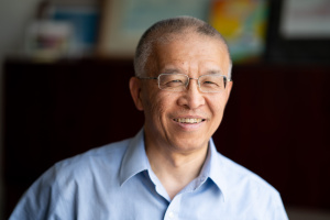 Headshot of lecturer Gang Chen smiling, blurred background
