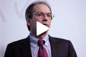 John Lienhard in front of white background with play button on image