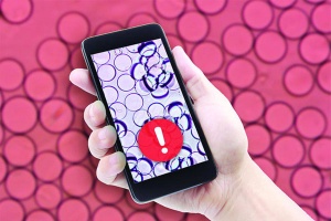 Hand holding smart phone with warning