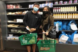 Two students holding grocery baskets at store