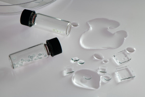Two vials with hydrogel particles inside, with water next to the table. 