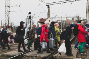 Lviv, Ukraine - March 3, 2022: Having just disembarked a train, people walk with their luggage across the tracks in Lviv. 