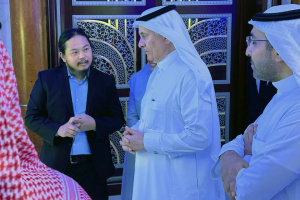 Quantum Wei in a conversation with a man wearing traditional Emirati attire, standing by an ornate arabesque archway